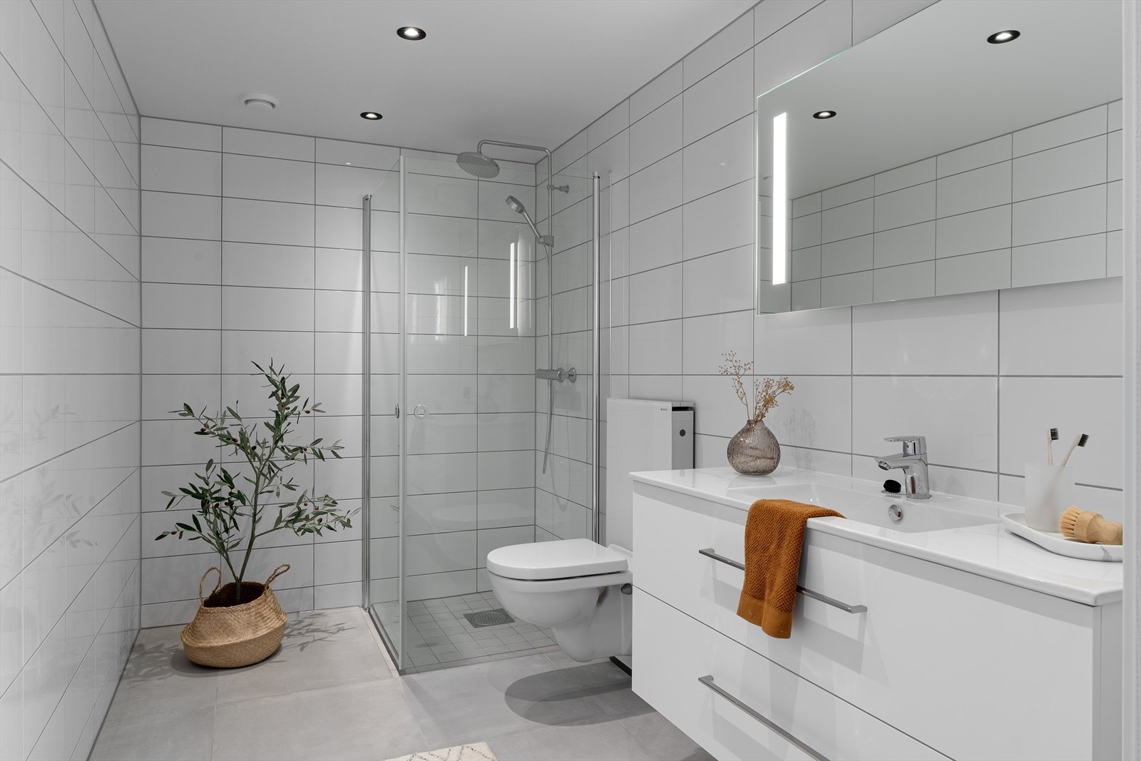 Flott helfliset bad med vegghengt wc, dusjhjørne og varme i gulv for ekstra komfort. Badet fremstår som lyst og åpent med pen baderomsinnredning i hvit utførelse. Galleribilde