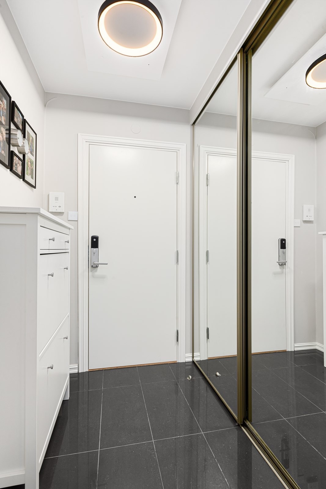 Innbydende entré med flislagt gulv og rikelig med oppbevaringsplass i skyvedørsgarderobe Galleribilde