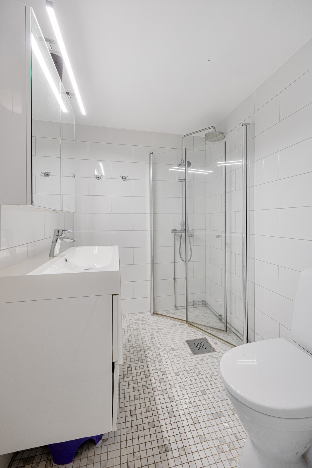 Baderomsinnredningen har hvite fronter og består av en heldekkende servant på en skuffeseksjon og et dobbelt speilskap med belysning. Galleribilde