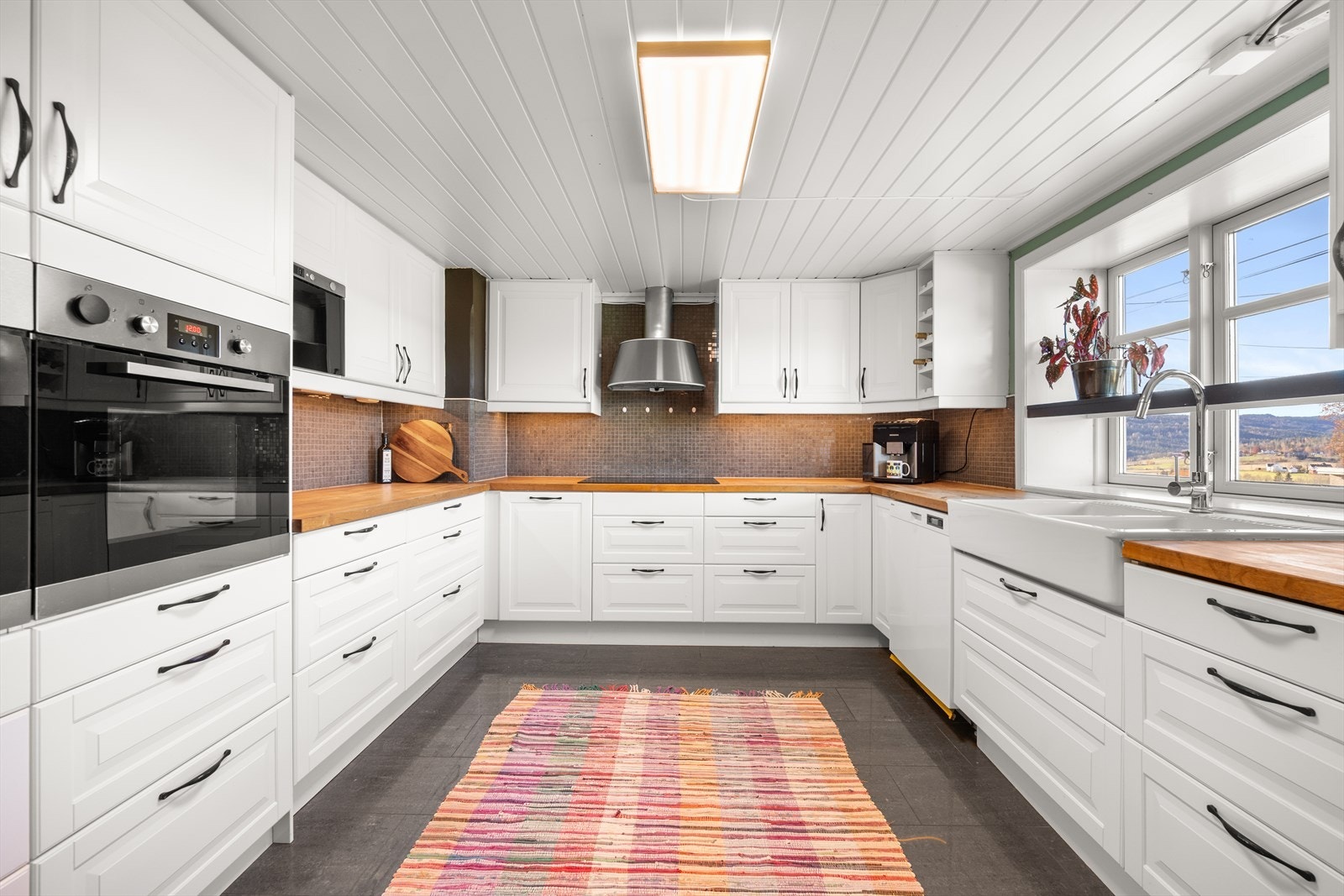 Romslig kjøkken med profilerte fronter og benkeplate i heltre Galleribilde