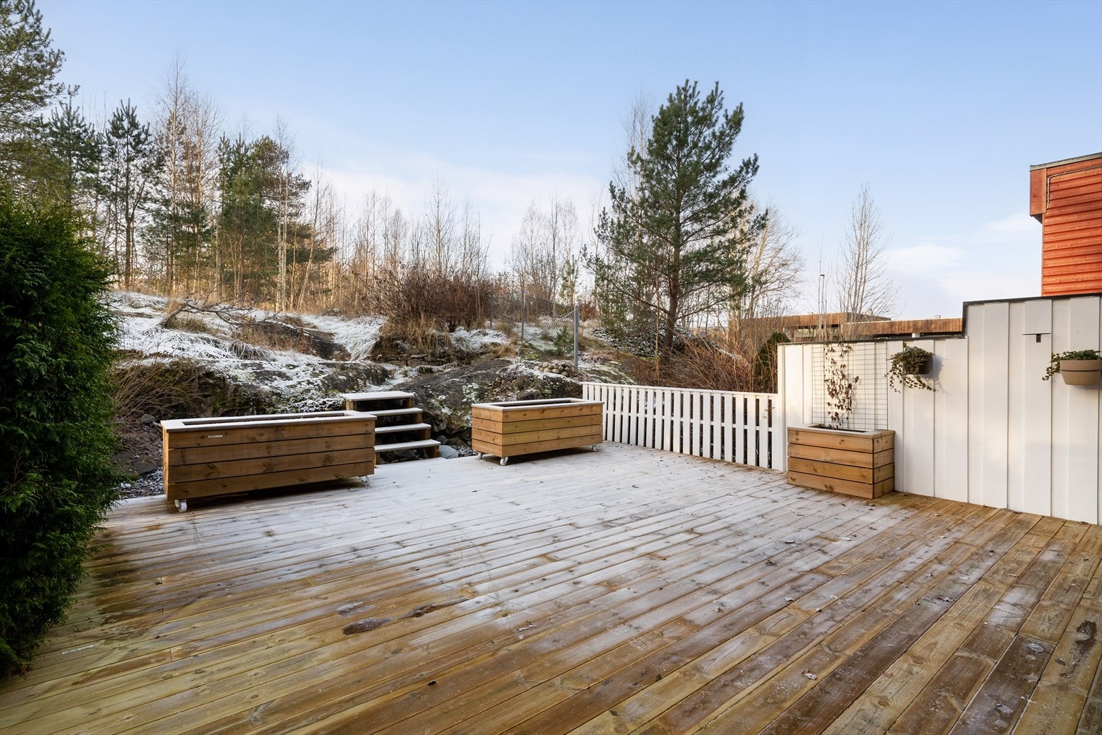 Skjermet for innsyn med levegg og hekk mot naboer. Det er etablert trapp fra terrassen opp til naturtomten ovenfor. Galleribilde