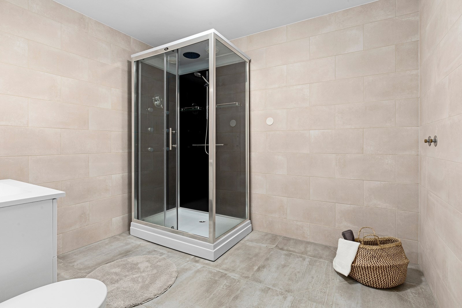 Badet er flislagt og innehar dusjkabinett med flere funksjoner, toalett og servant - i tillegg er det opplegg for enten badekar eller badstue i tillegg Galleribilde