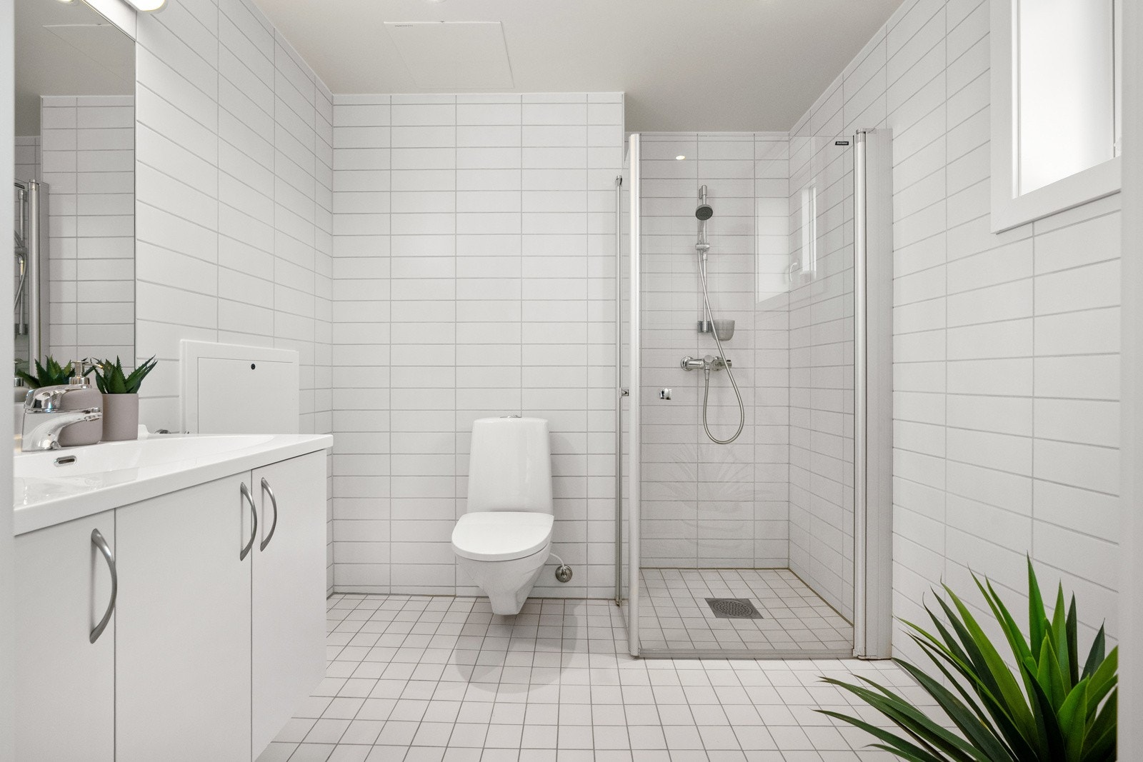 Her finner du vegghengt servantskap, speil og overlys med stikkontakt over servant, dusjhjørne med innfellbare glassdører og dusjarmatur med hånddusj, samt vegghengt toalett. Galleribilde