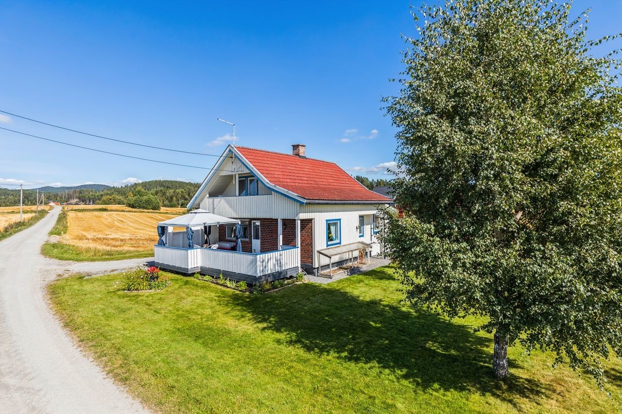 En innholdsrik enebolig med en stor låve, beliggende i et landlig og åpent landskap. Galleribilde