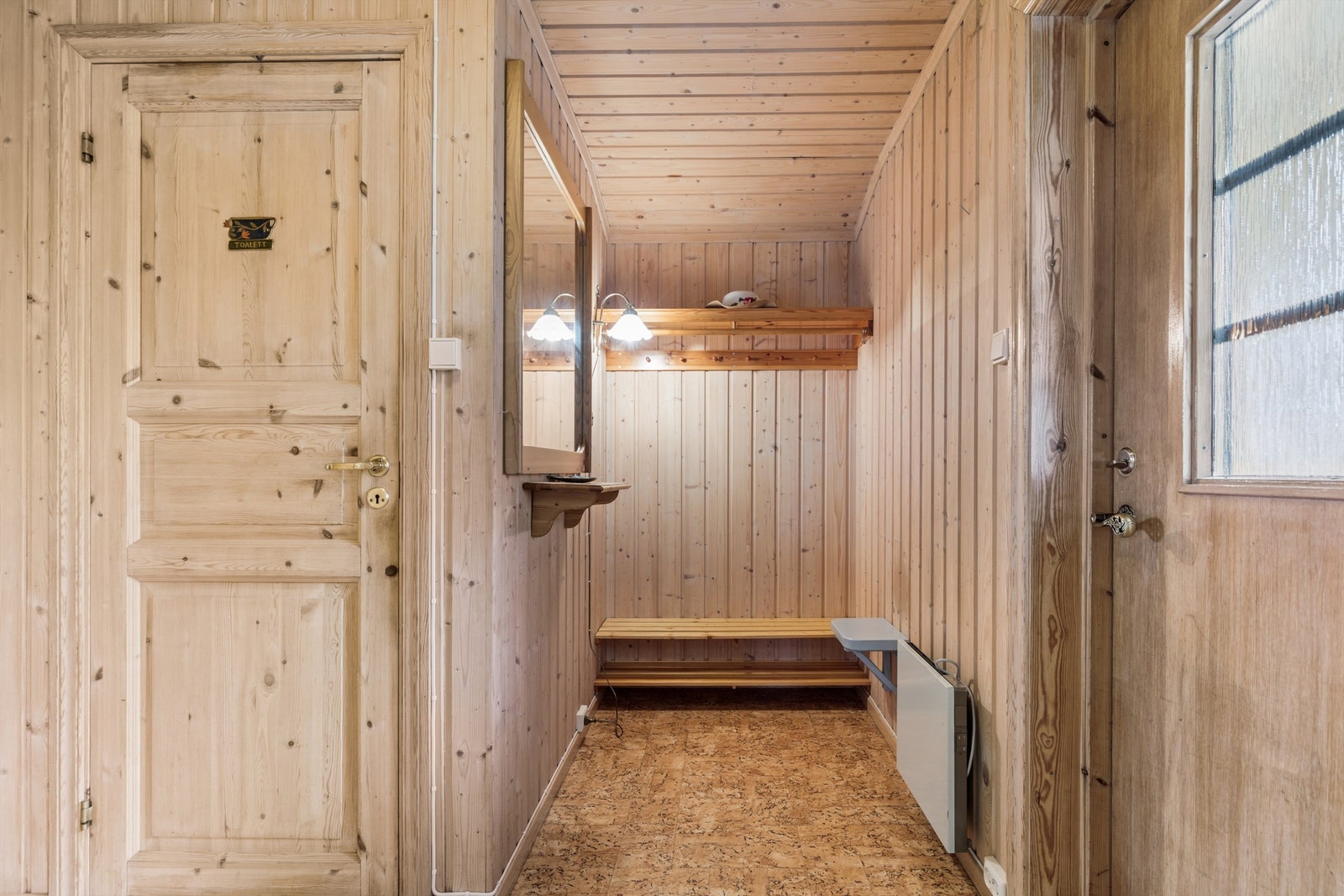 Velkommen inn i en lys entré med panelkledde vegger og adkomst til et separat toalettrom. Galleribilde