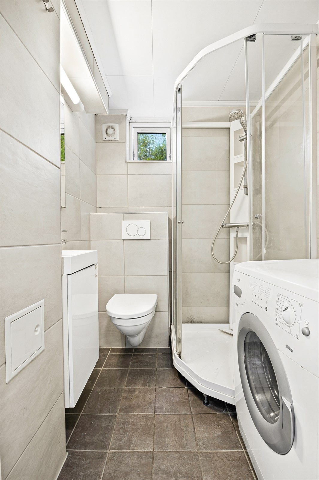 Fra gang er det adkomst til flislagt bad med innredning bestående av klosett, dusjkabinett og baderomsinnredning med speil. Badet har opplegg for vaskemaskin og tørketrommel Galleribilde