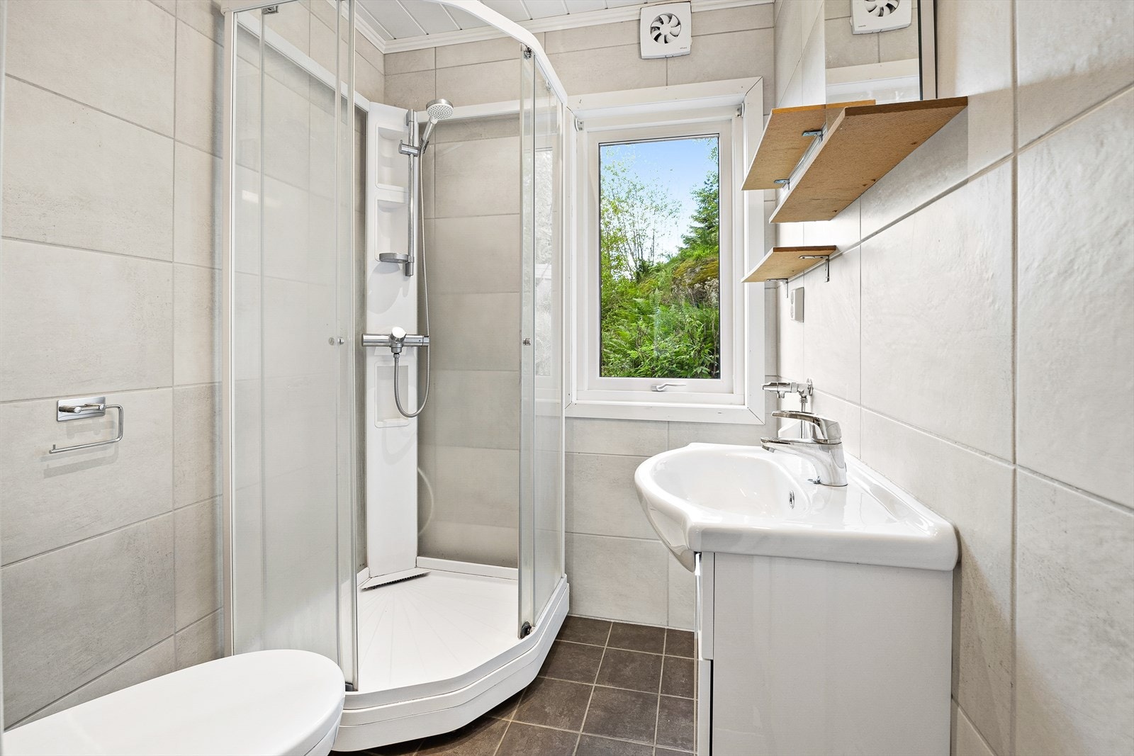 Pent bad med innredning bestående av klosett, dusjkabinett og baderomsinnredning med speil Galleribilde