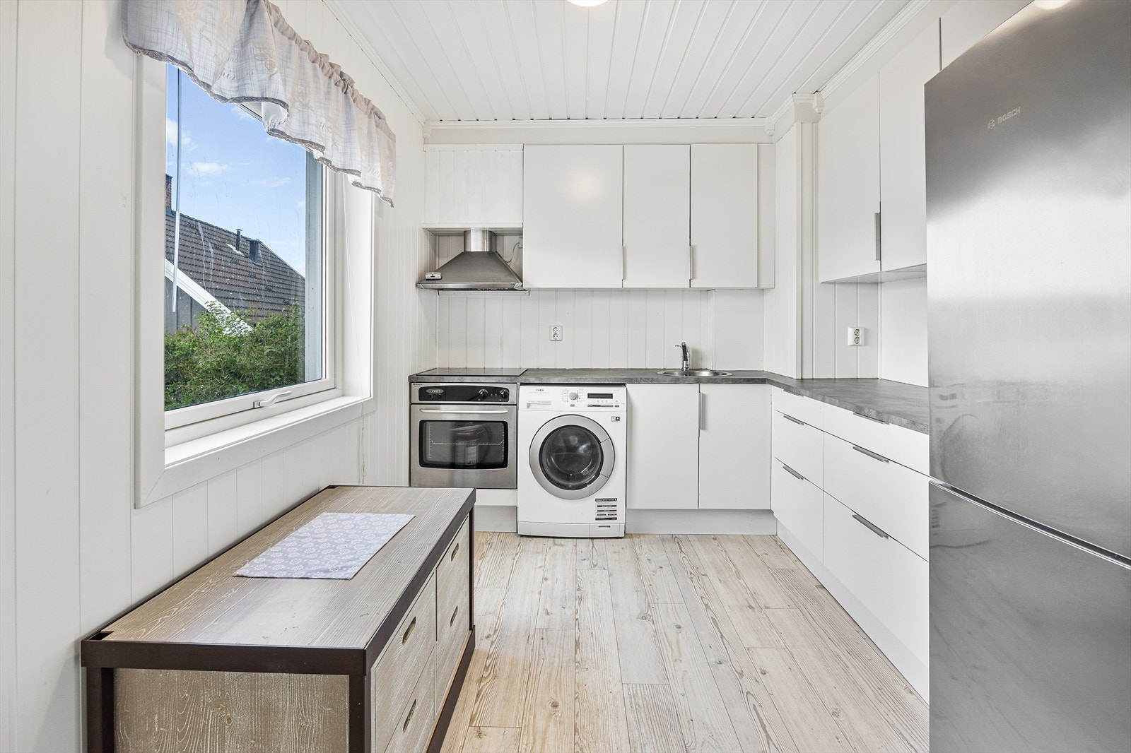 Kjøkkenet har integrert komfyr og platetopp og det er etablert en egen nisje for vaskemaskin Galleribilde