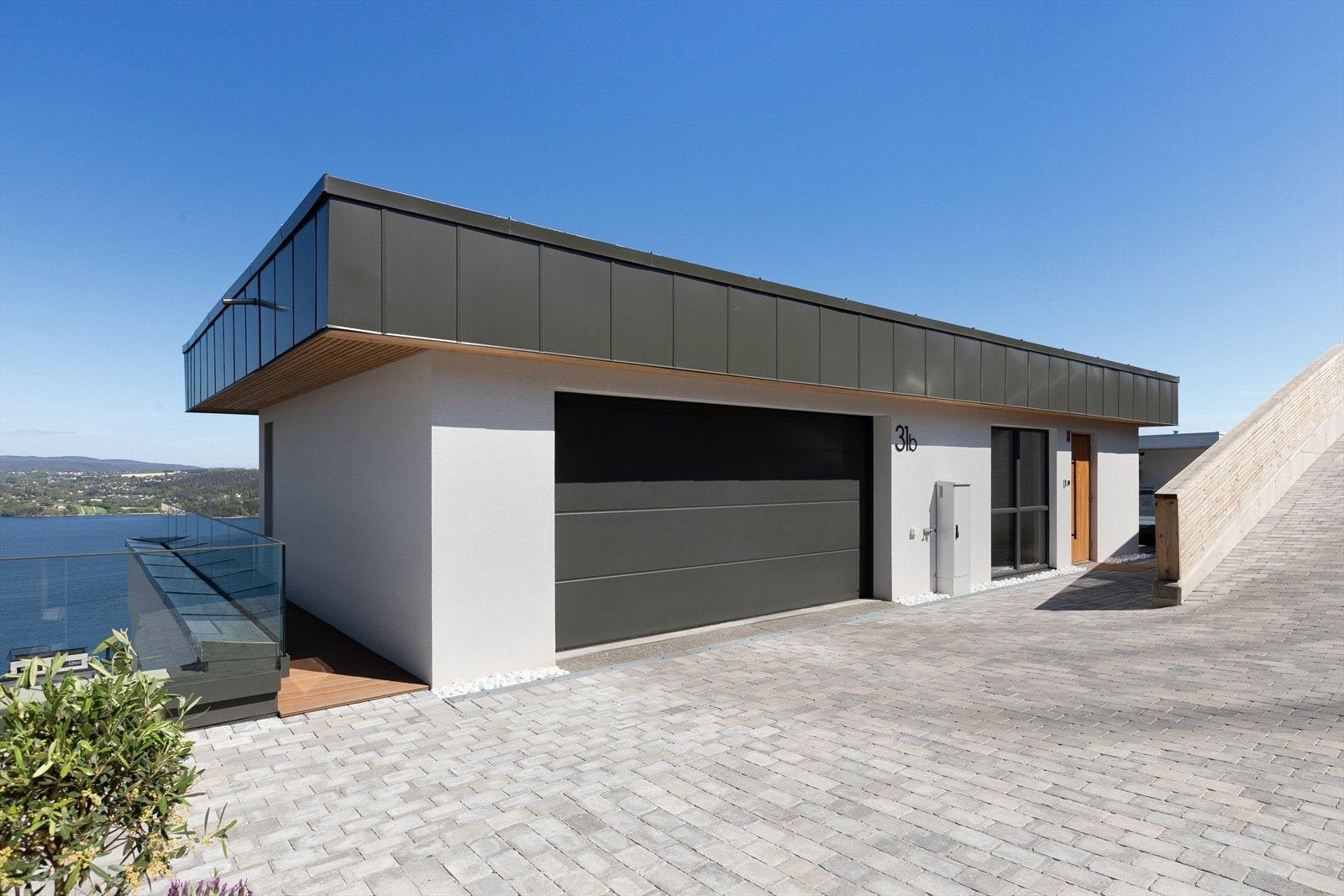 Oversiden er påkostet med spilrekkverk, tilpasset dreneringssystem, granittmur, beplantning med sedum og magnolia, grus og hekk Galleribilde