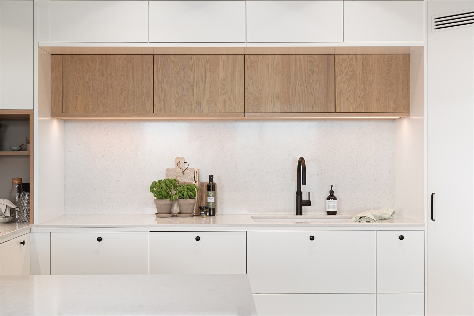 Kjøkkenet har en flott nisje med eikedetaljer i overskap med innfelt belysning Galleribilde