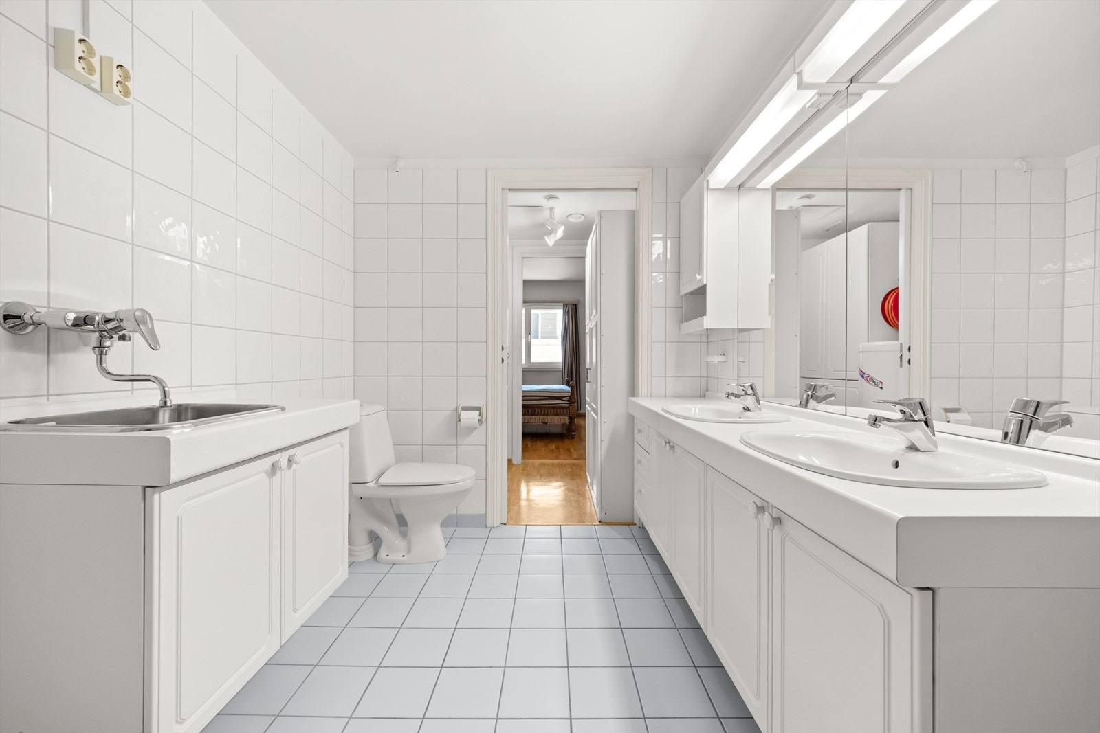 Badet er utstyrt med dobbel servant med underskap, stor speil og lys, dusjhjørne og toalett, samt vaskeromsdel Galleribilde