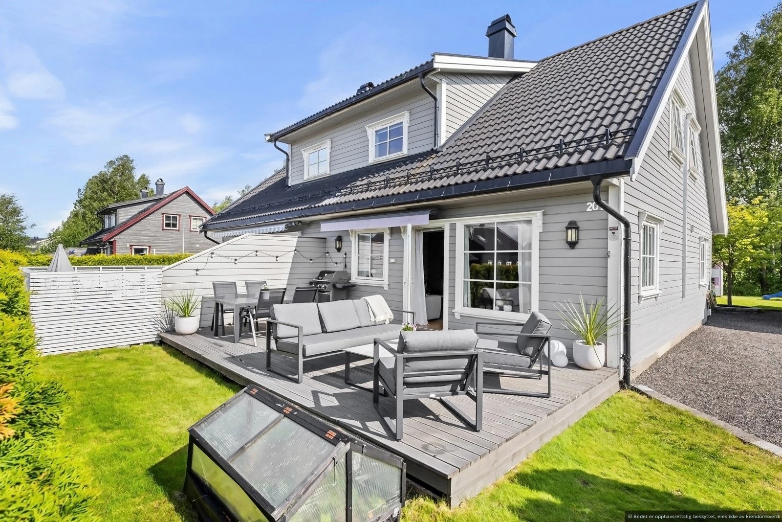 Stor terrasse med god plass til utemøblement og hage på byggets forside Galleribilde