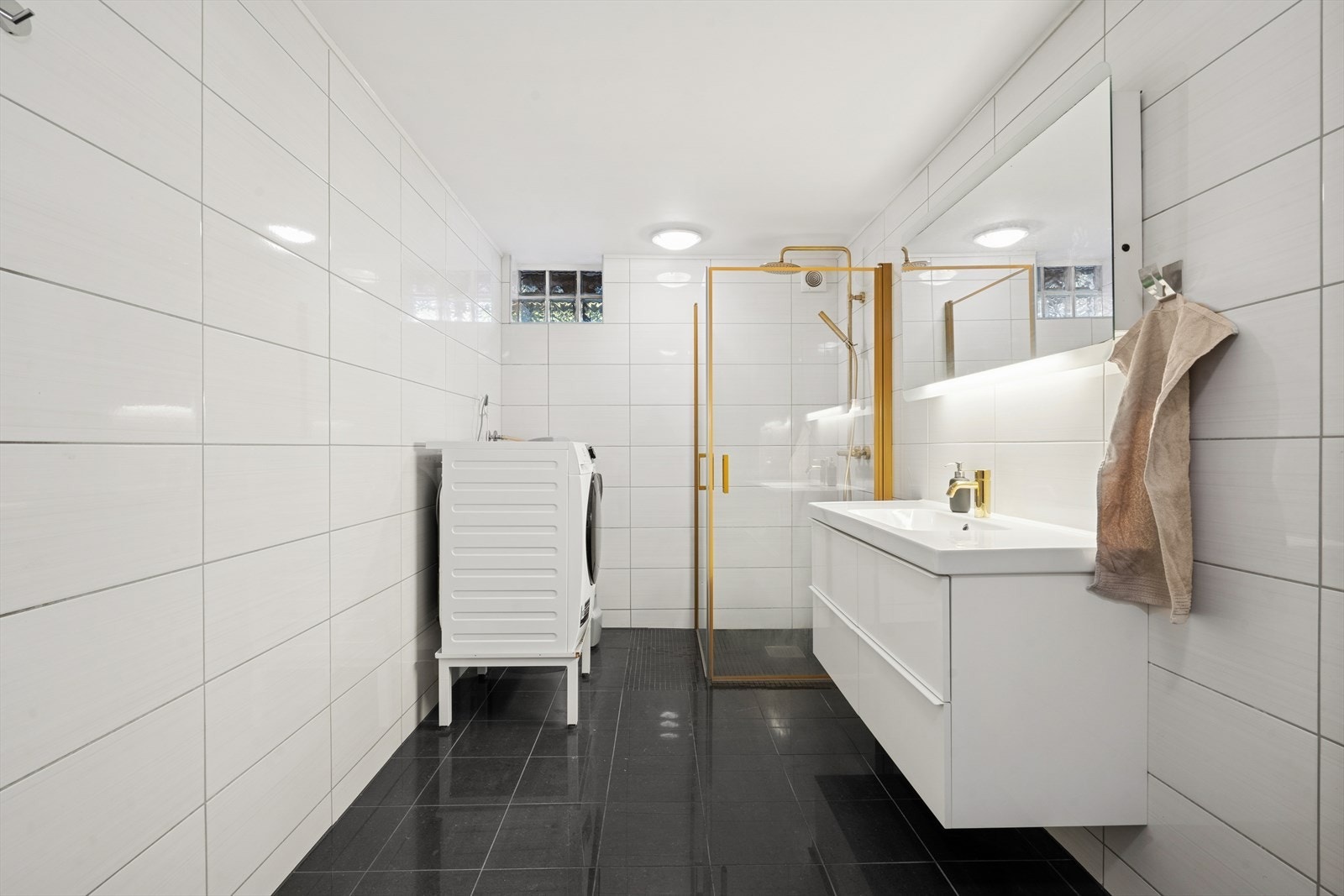 Badet har varmekabler for ekstra komfort, opplegg for vaskemaskin, varmtvannsbereder i rommet og elektrisk vifte på vegg. Galleribilde