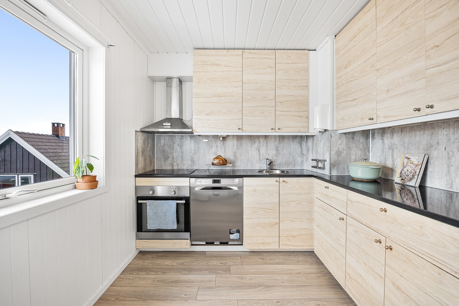 Pent IKEA kjøkken bestående av over- og underskap samt skuffer med laminat benkeplate og integrert komfyr, platetopp og opppvaskmaskin Galleribilde