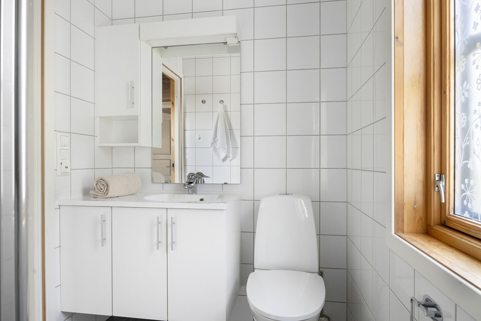Hyttas baderom er stilrent og moderne med lyse fliser på vegger og gulv Galleribilde