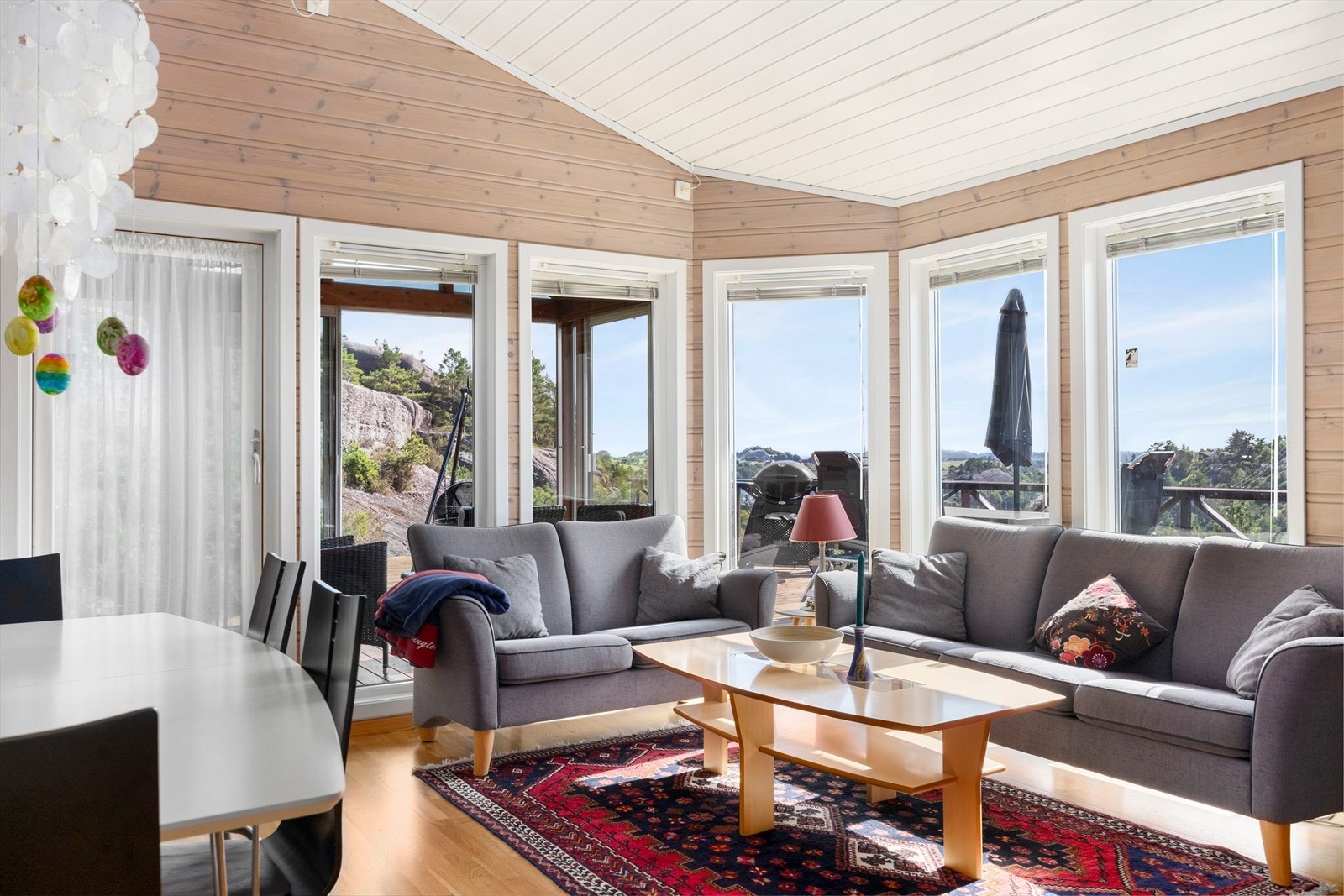 Stua preges av store vindusflater, høy himling, og en åpen planløsning mot kjøkkenet, noe som gir et luftig og lyst oppholdsområde. Galleribilde