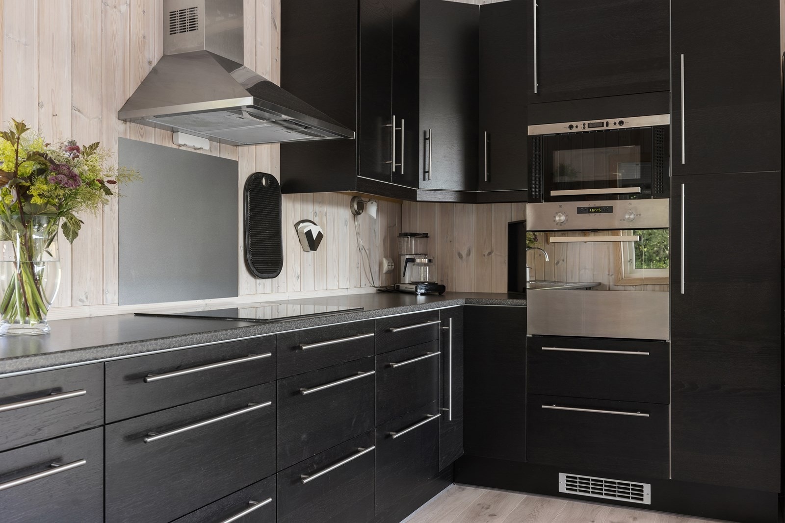 Kjøkkenet har en moderne og mørk innredning med slette fronter og en solid laminert benkeplate som inkluderer en nedfelt vask. Galleribilde