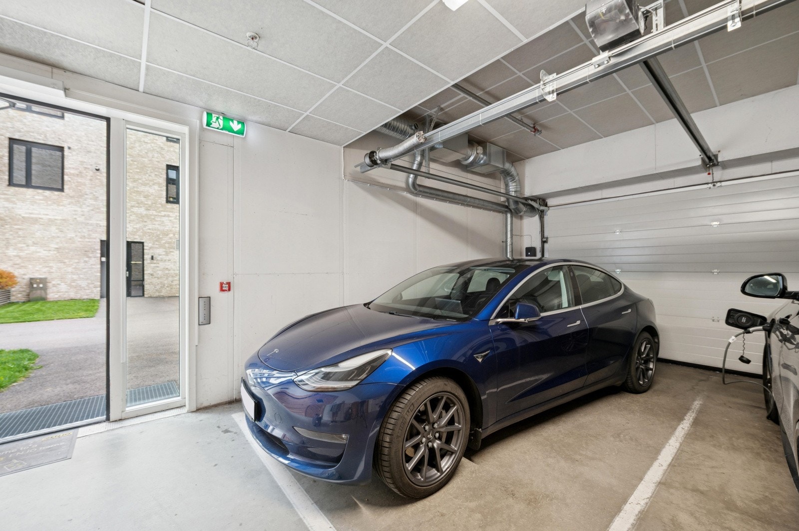 Romslig endeparkeringsplass på bakkeplan med elbillader og enkel adkomst via heis. Galleribilde