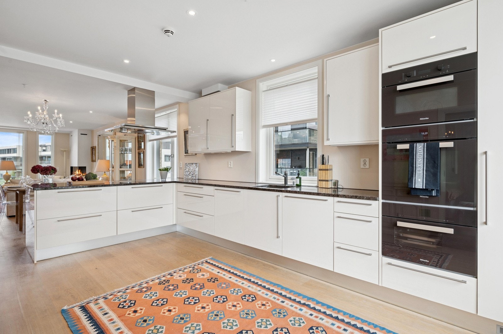 Moderne kjøkken med Crown-innredning, lyse slette fronter, benkeplate i eksklusiv larvikitt og integrerte Miele-hvitevarer. Galleribilde