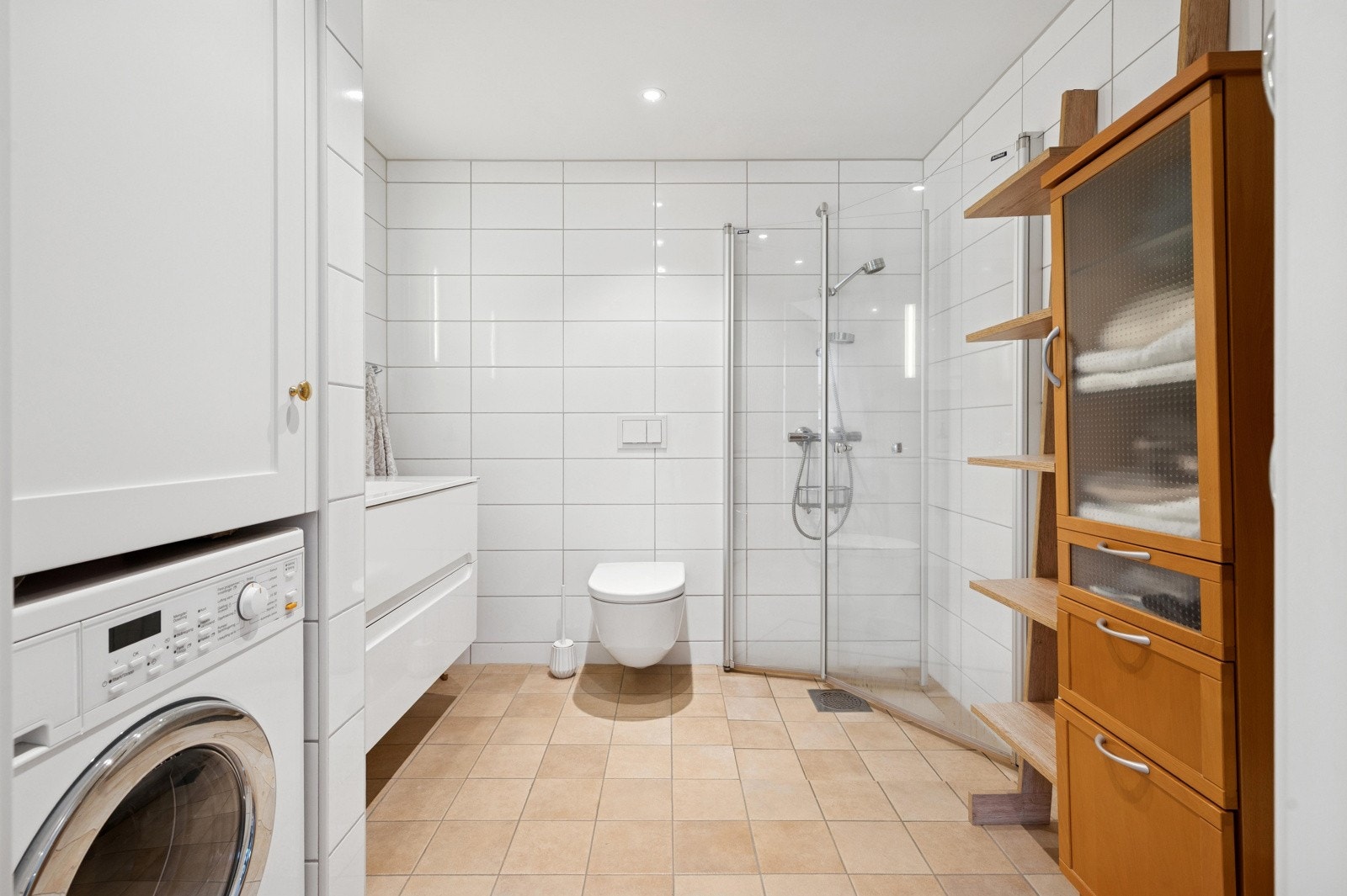 Moderne bad med plassbygd nisje fra JH Interiør for vaskemaskin, nedsenket himling og innfelte downlights. Galleribilde