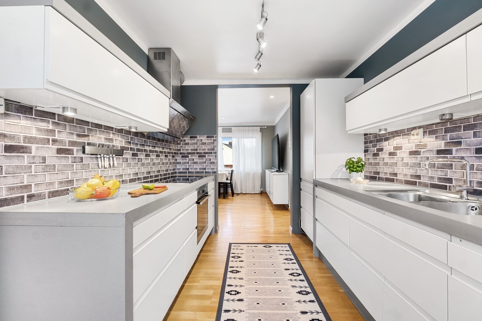 Kjøkkeninnredningen er stilren med hvite glatte fronter og benkeplate i laminat med nedfelt kjøkkenvask Galleribilde