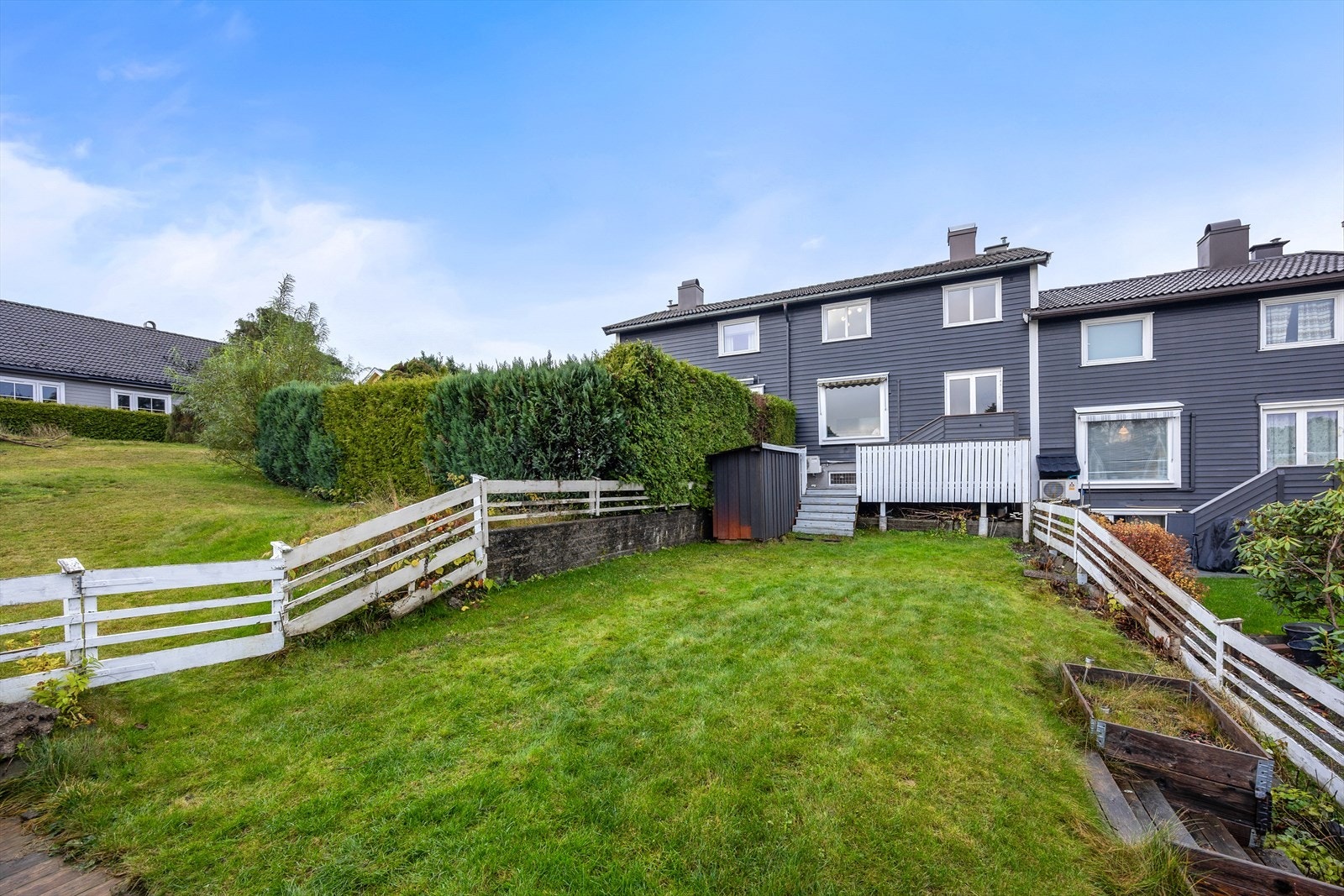 Lett skrånende og inngjerdet hage med gressplen Galleribilde