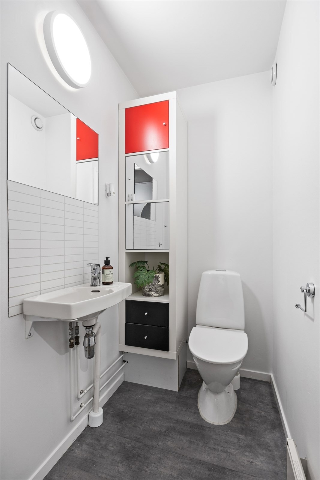 Boligen har også et praktisk toalettrom med pvc-flise og malte veggflater. Toalettet er innredet med vegghengt servant med speil samt belysning på vegg, gulvstående toalett og gulvstående høyskap. Galleribilde