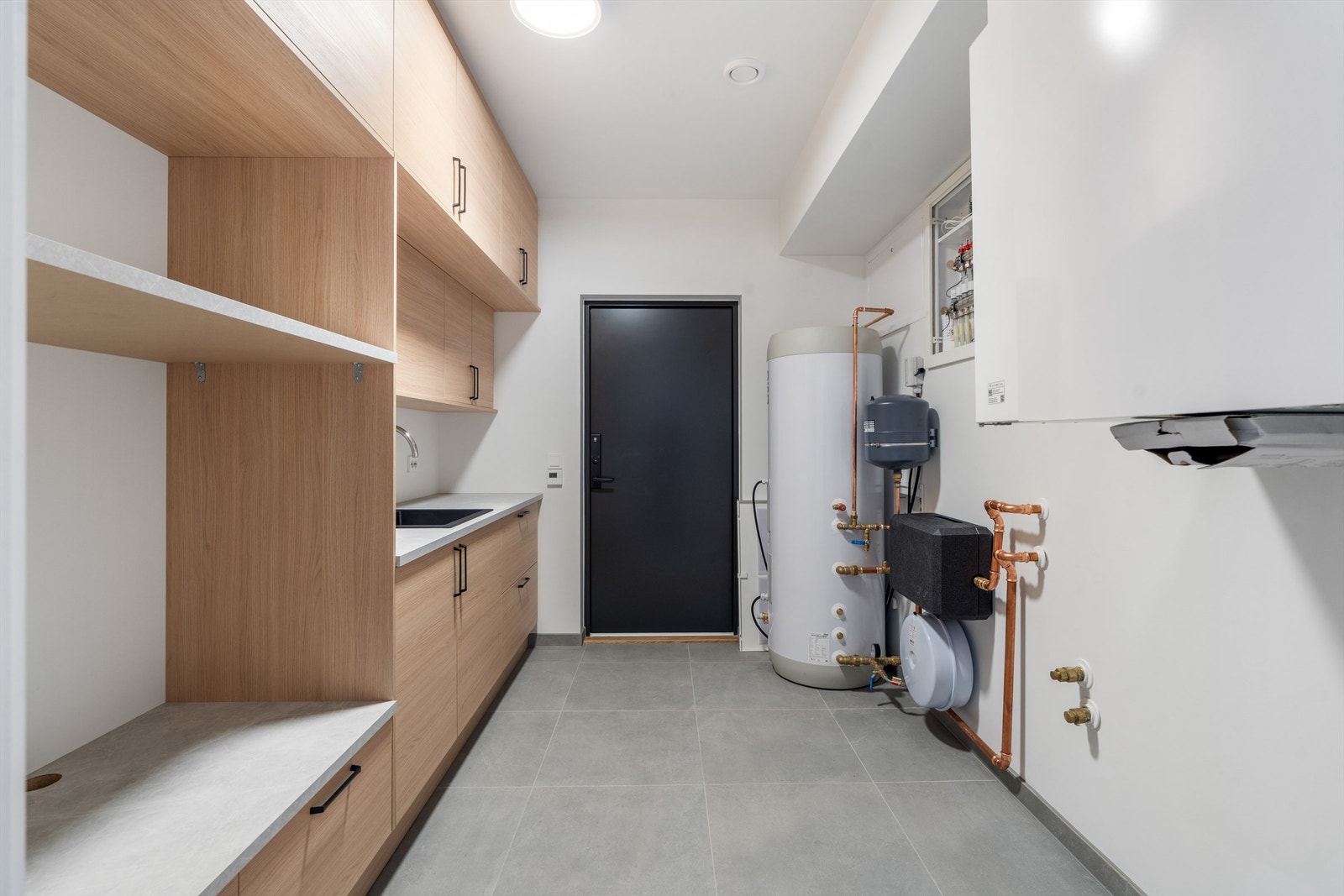 Innredningen på vaskerommet har godt med skapplass, vask og opphøyet plassering for hvitevarer. Døren går ut til carport / uteareal, slik man går trygt og tørrskodd fra bilen og inn i huset. Galleribilde