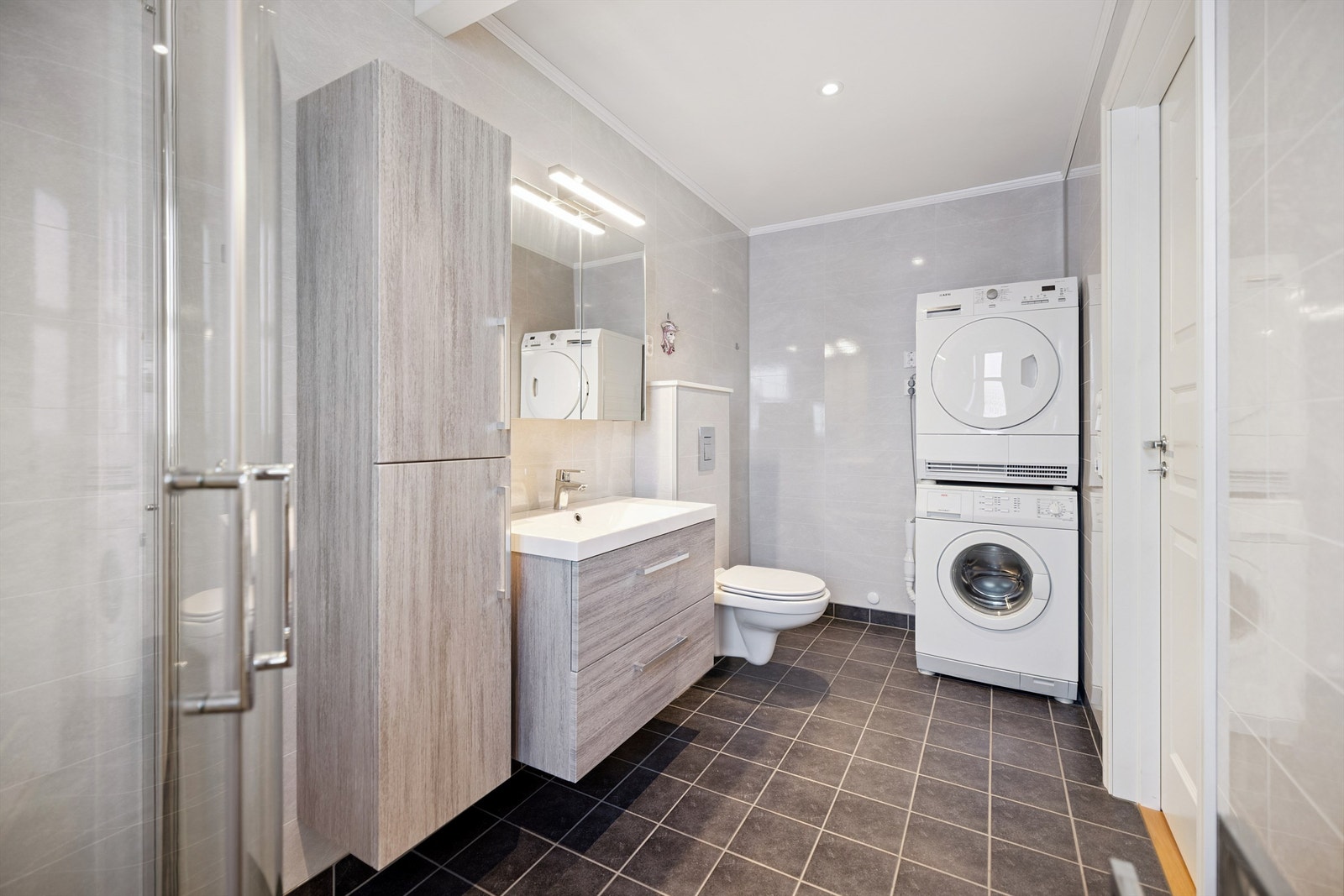 Her er det vegghengt toalett, dusjhjørne med glassdører og opplegg for vaskemaskin. Galleribilde