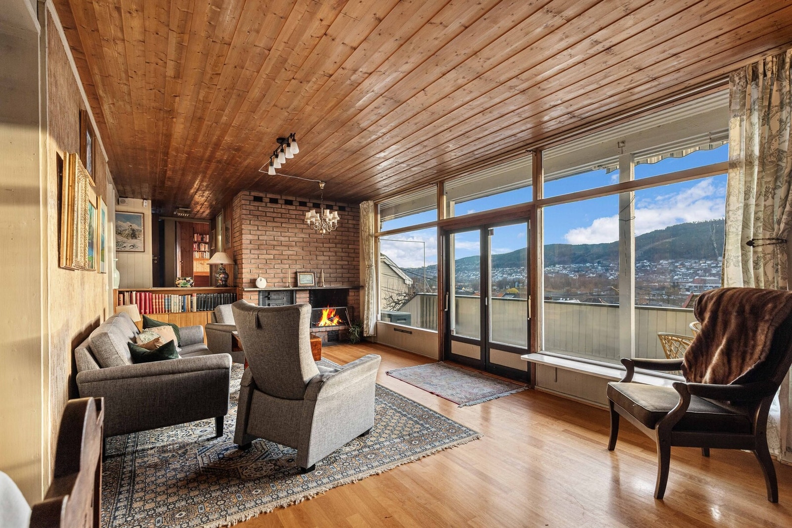 Rommet har parkett, trepanel i taket, peis, store vinduer og utgang til balkong med utsikt Galleribilde