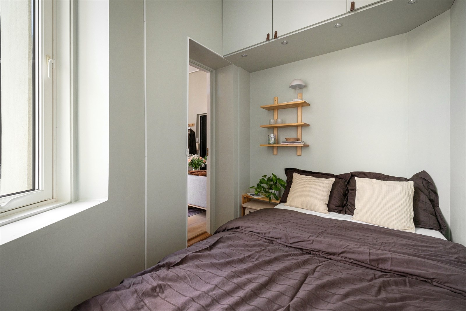 Plassbesparende, vegghengt skap over sengen sikrer godt med lagringsplass. Galleribilde