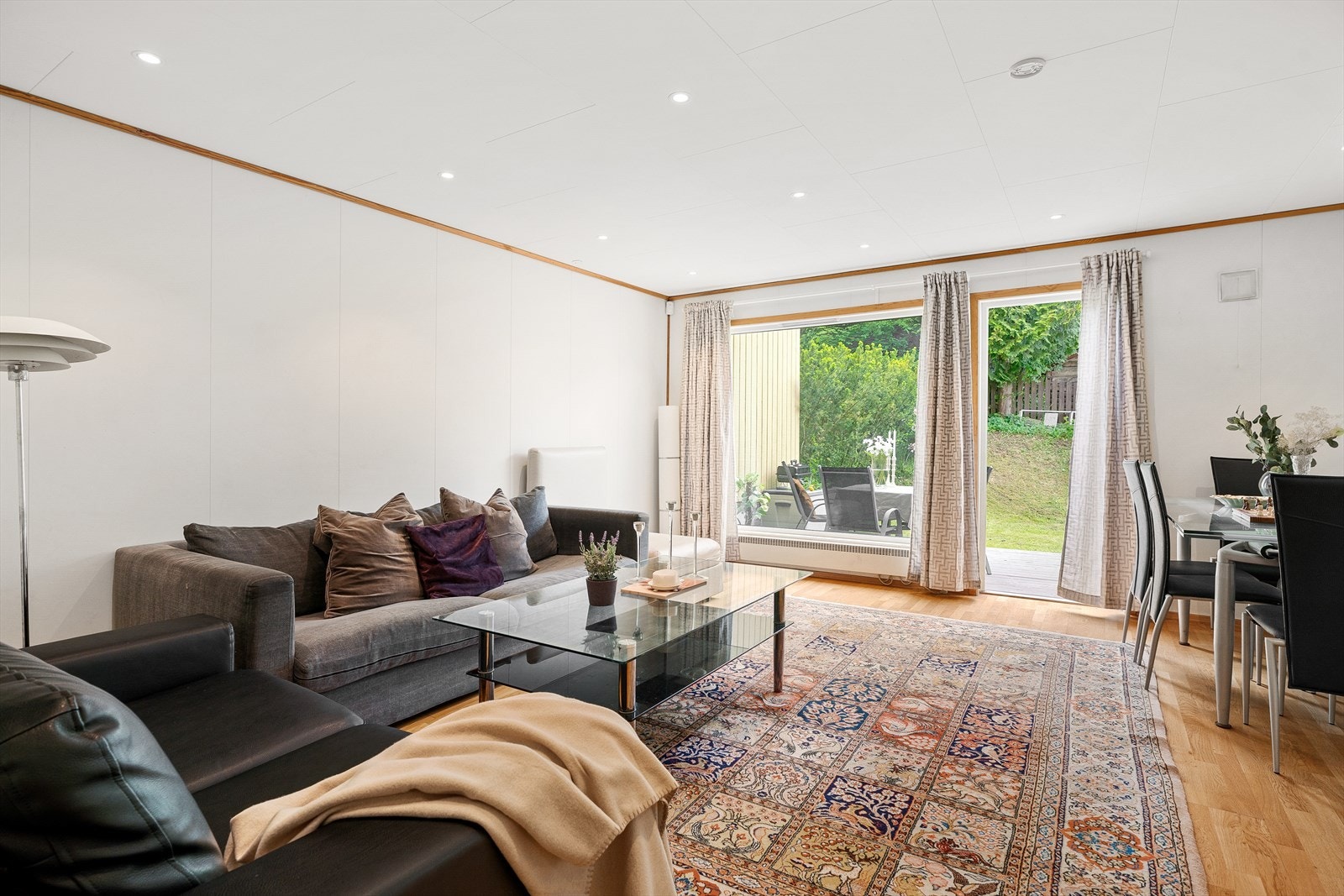 Den romslige stuen gir naturlig plass til både sofa- og spisegruppe, og store vindusflater slipper inn rikelig med dagslys. Galleribilde