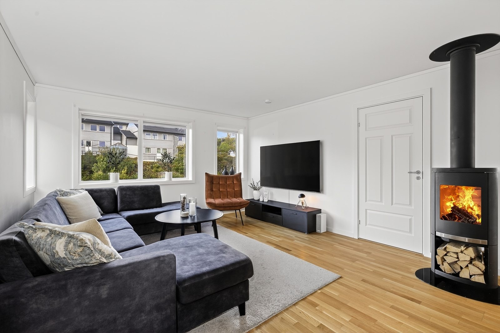 Stua rommer også en raus sofagruppe og annen mindre møblering. Sentralt i rommet er det en moderne vedovn med stålrør og glassdør for lun og god varme på kalde dager. Galleribilde