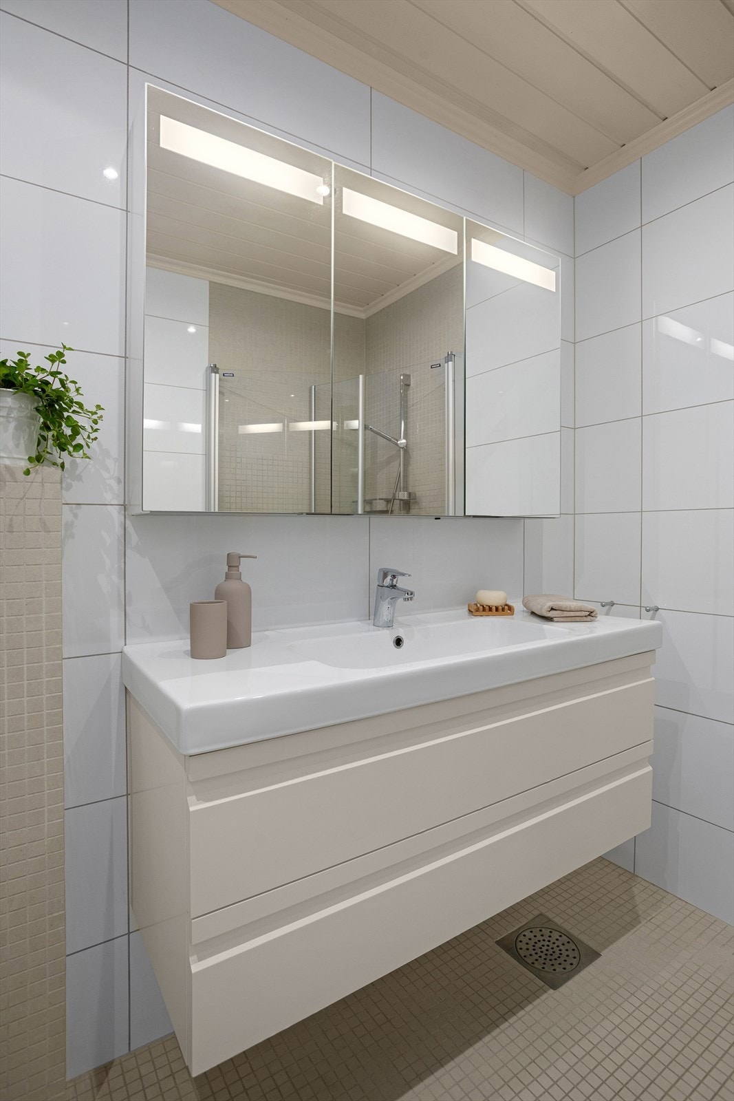 Badet er utstyrt med heldekkende servant med underskap og speilskap Galleribilde