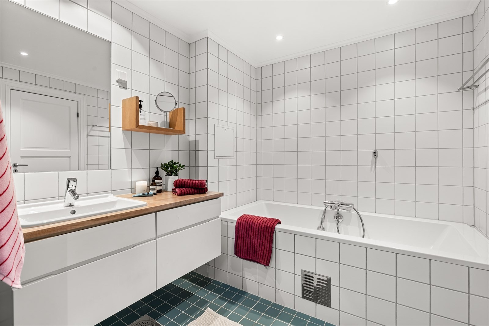 Innredningen består av en romslig dusjnisje, innfliset badekar, vegghengt toalett og en nedfelt servant med tilhørende baderomsinnredning som gir både oppbevaringsplass og en praktisk hverdagsløsning. Galleribilde