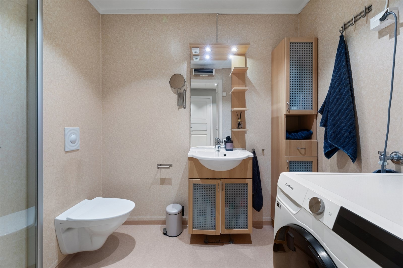 Badet/vaskerommet er innredet med vegghengt toalett, servant over praktisk skapinnredning, speilhylle med belysning, vegghengt skap og opplegg for vaskemaskin. Galleribilde