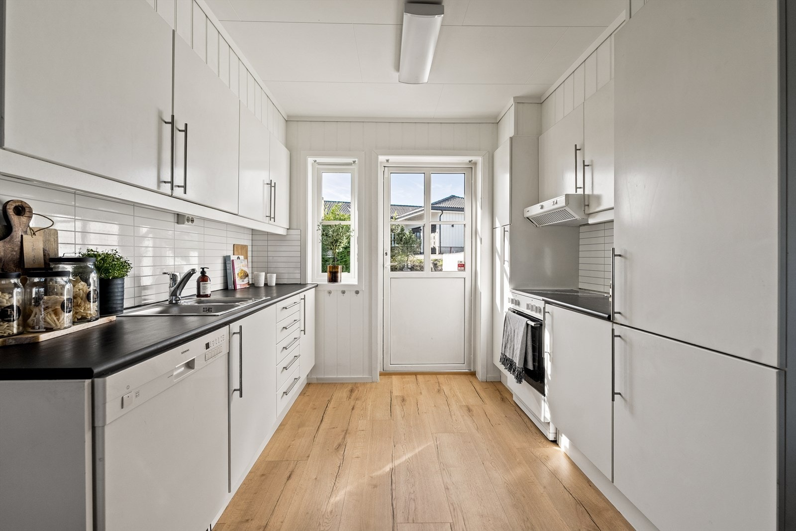 Kjøkkeninnredning med hvite glatte fronter, heltre benkeplater, dobbel stålkum med ett-greps blandebatteri. Galleribilde