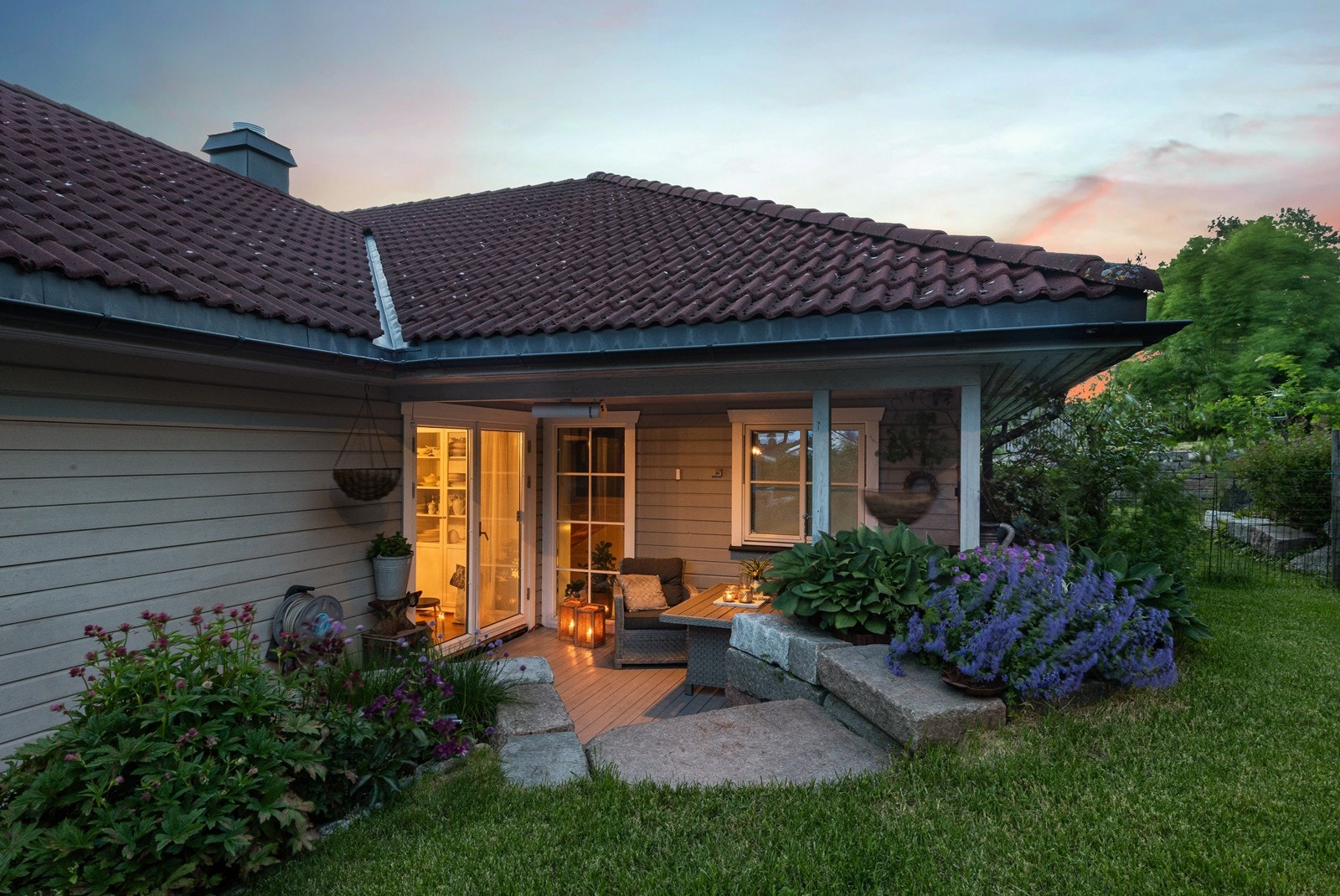 Steintrapp fører videre opp til grønn hage, og verandaen strekker seg videre til boligens syd- og vestside. Galleribilde