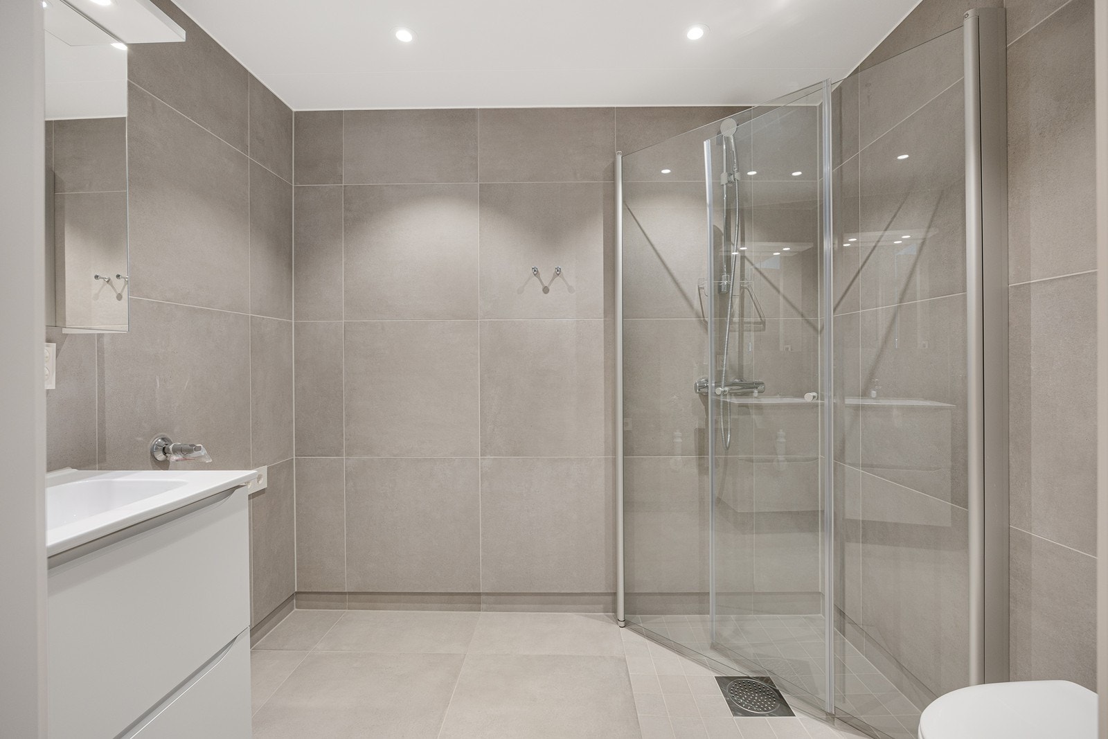 I baderommet er det store og lekre fliser som gir moderne preg. Rommet har praktisk spotbelysning i tak og vannbåren gulvvarme. Galleribilde