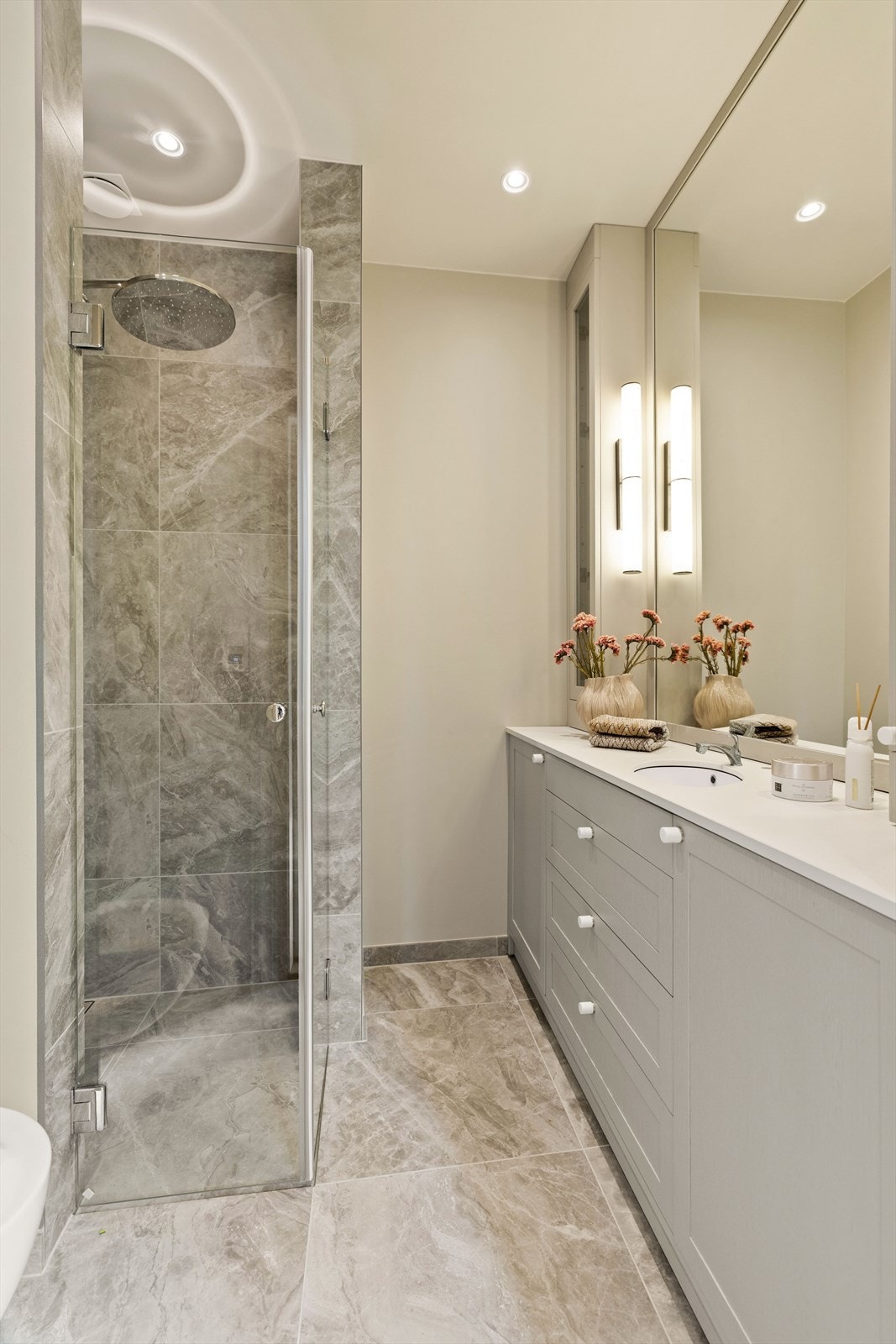 Lekkert bad med marmorfliser i størrelse 60x60 cm. Snekkerbygget servantskap med benkeplate i dekton. Vegglampe fra Heathfield Co. Galleribilde