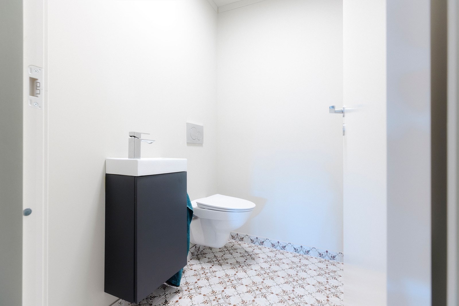 Toalettrommet har lekre fliser på gulv, vegghengt toalett og sort servant i moderne stil. Galleribilde