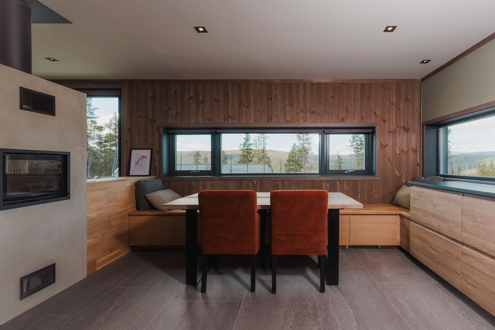 Det er delvis åpen løsning mellom kjøkken og stue. Rommene er avdelt med halvvegg og en nydelig peis med stort flammebilde. Galleribilde