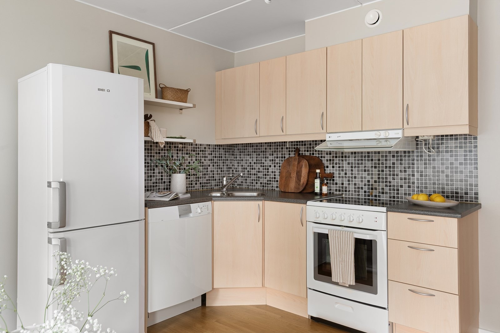 Kjøkkenet er lettstelt med glatte overflater og flis over kjøkkenbenk Galleribilde