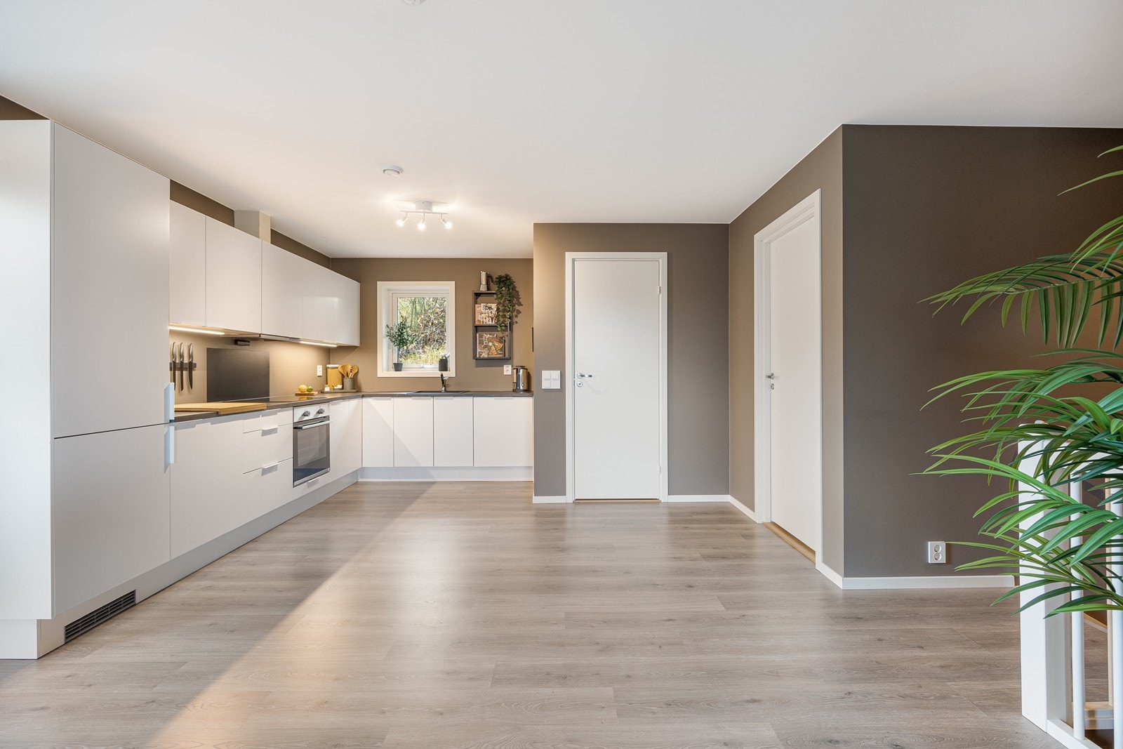 Innredningen er tidløs, med hvite, glatte fronter, nedfelt oppvaskkum og mørk benkeplate av laminat. Galleribilde