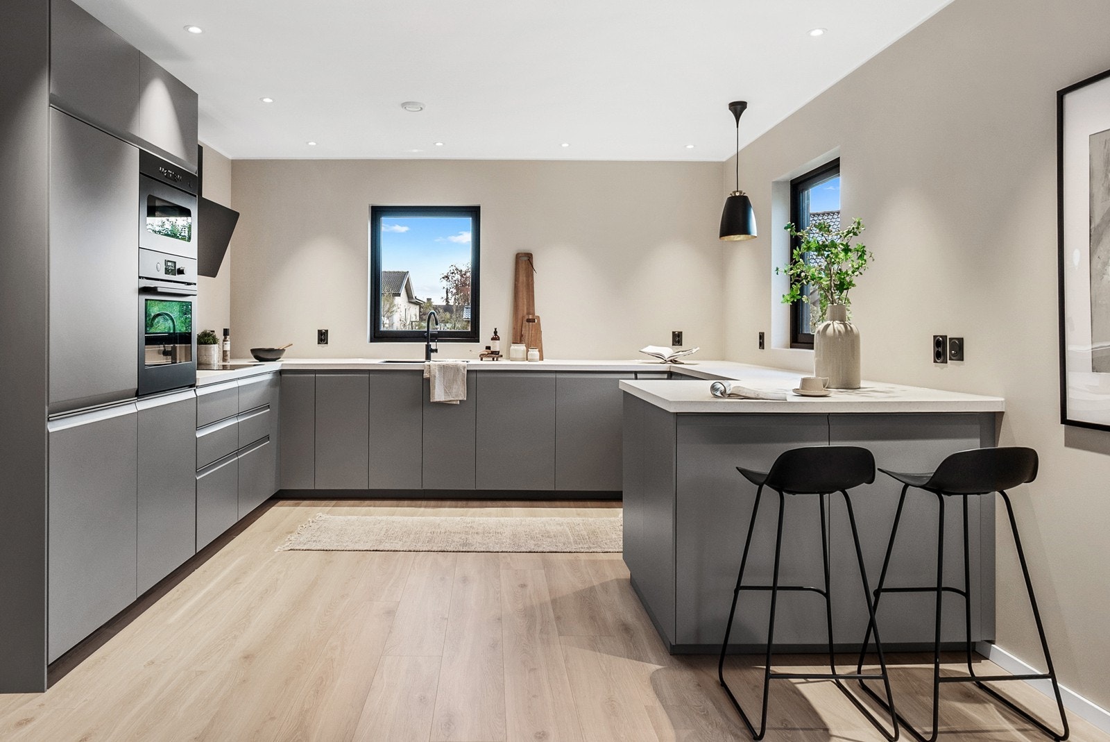 Kjøkkenet er både funksjonelt og stilrent, med slette fronter og lys laminat benkeplate. Galleribilde