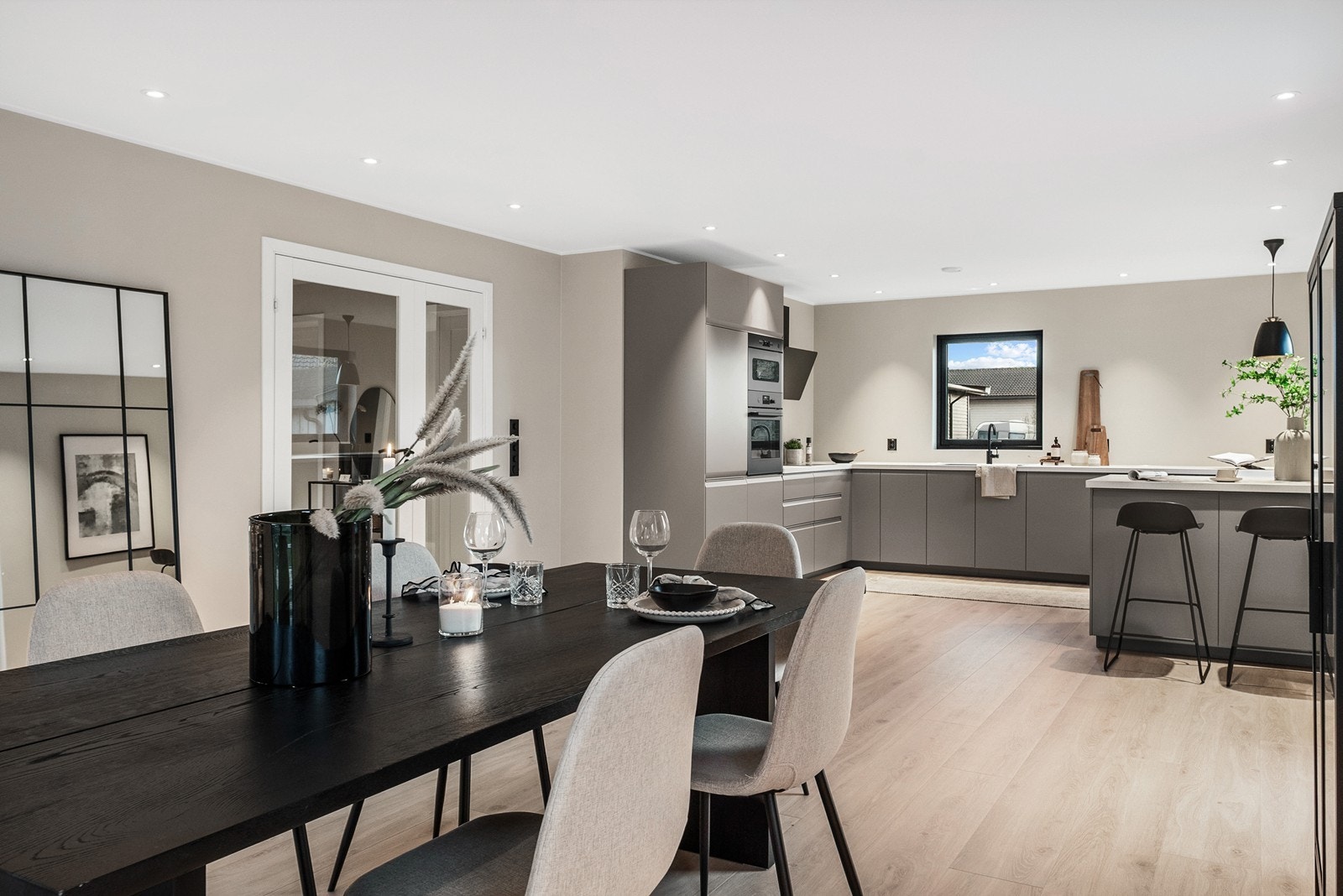 En tofløyet glassdør leder videre inn til boligens hovedrom, en romslig og åpen stue- og kjøkkenløsning med store vinduer og utstrakt bruk av downlights. Galleribilde