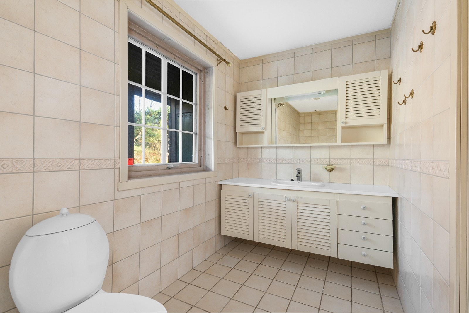 Badet er innredet med lyse fliser på både vegger og gulv. Det er bred innredning, skapoppbevaring og speil. Galleribilde