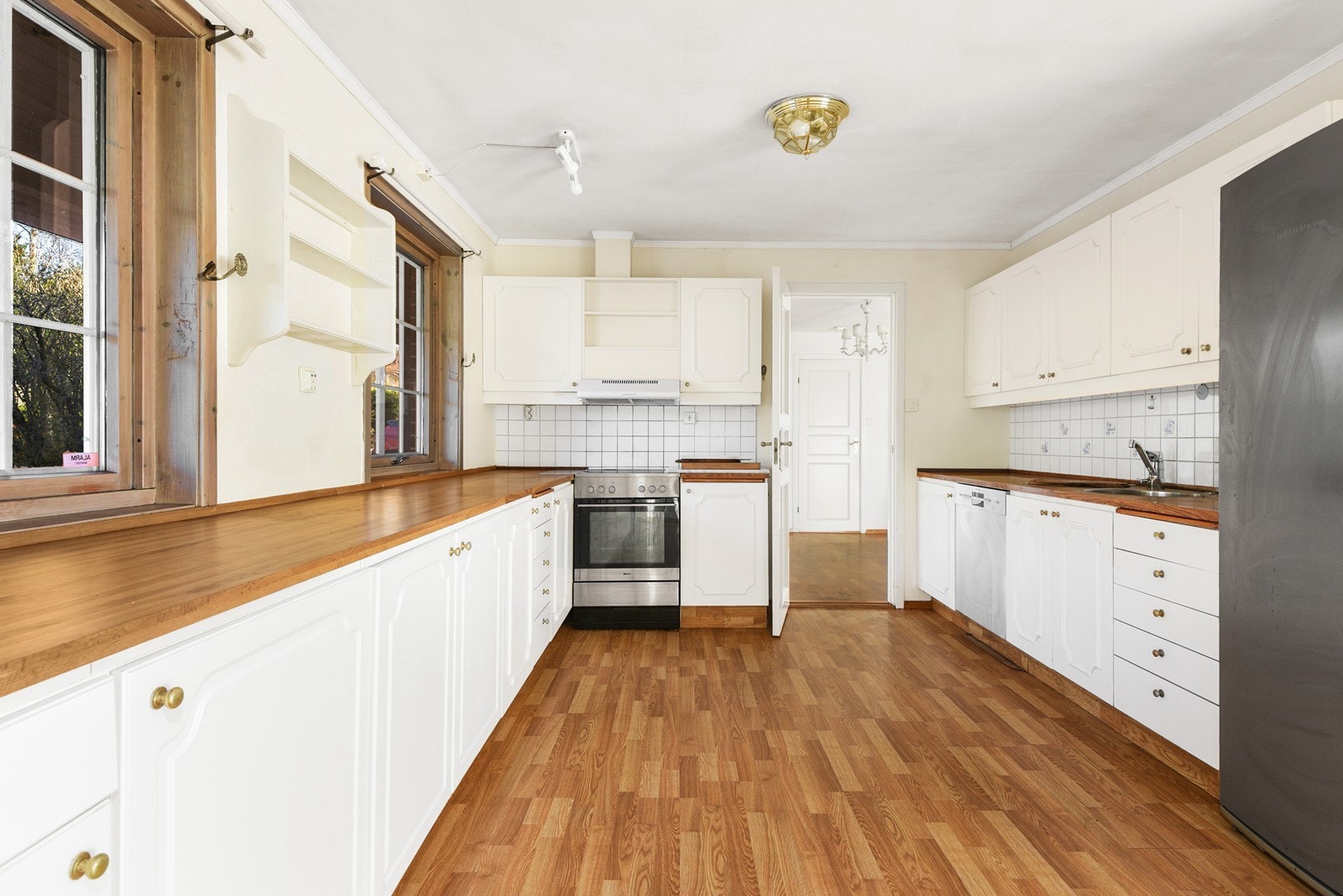 Kjøkkenet har malte fronter og gode arbeidsflater langs begge sider av rommet. Laminert benkeplate med fliser over benk gir et klassisk uttrykk. Her er det innbygget oppvaskmaskin og kjøkkenventilator med avtrekk ut. Galleribilde