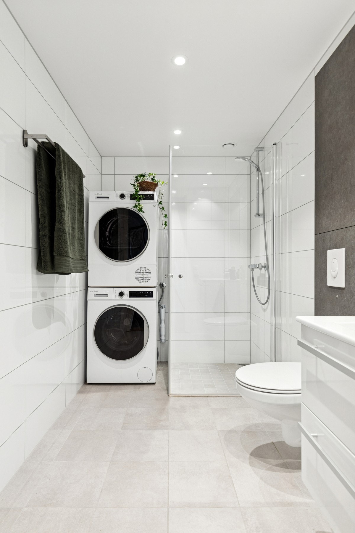 Badet er et prefabrikkert baderomsmodul fra byggeår, med fliser på både gulv og vegger, gulvvarme og downlights i himling. Galleribilde