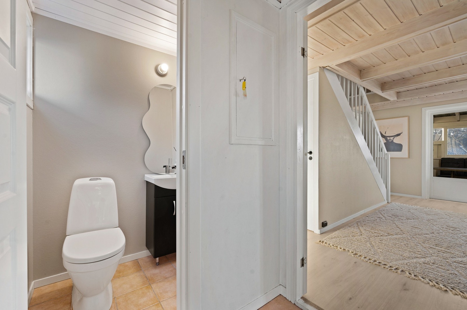 Praktisk toalett like inn ytterdøren med fliser på gulv og varmeovn på vegg. Galleribilde